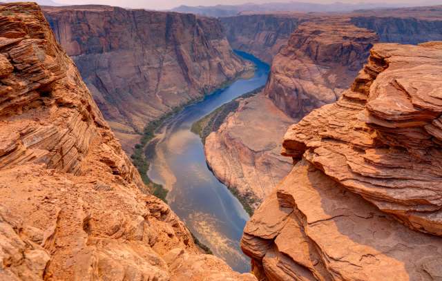 A river winds through a canyon surrounded by rocky cliffs and desert terrain.