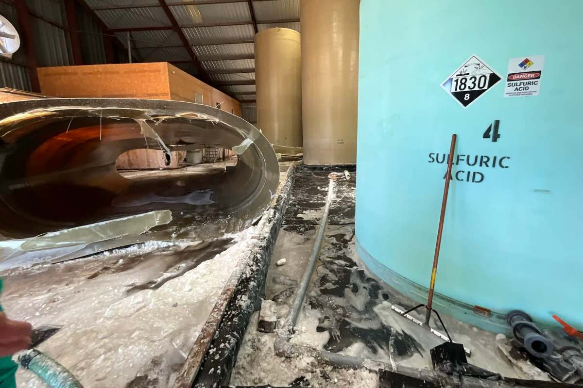 An industrial space with large storage tanks, a pipe, and a curved metal structure on the floor.