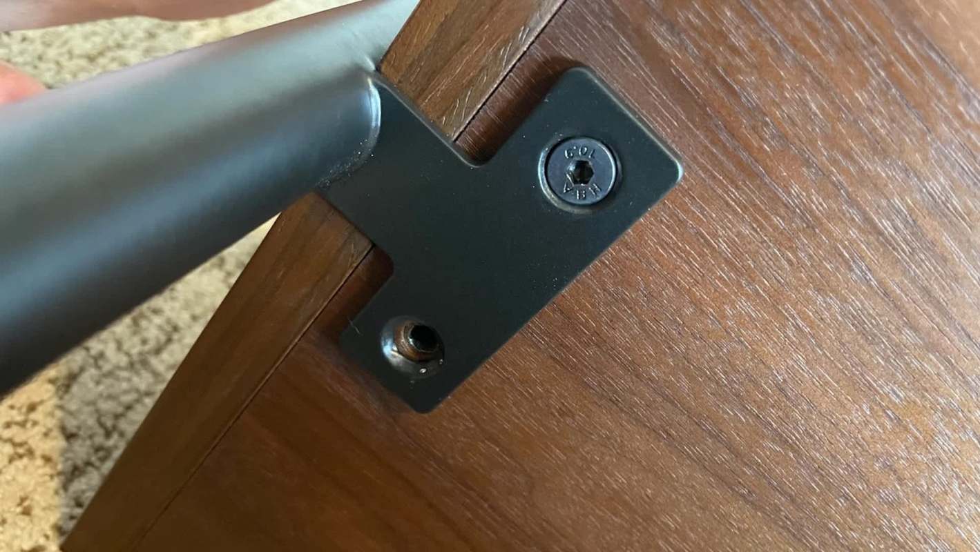 A black metal bracket attached to a wooden surface with a screw.