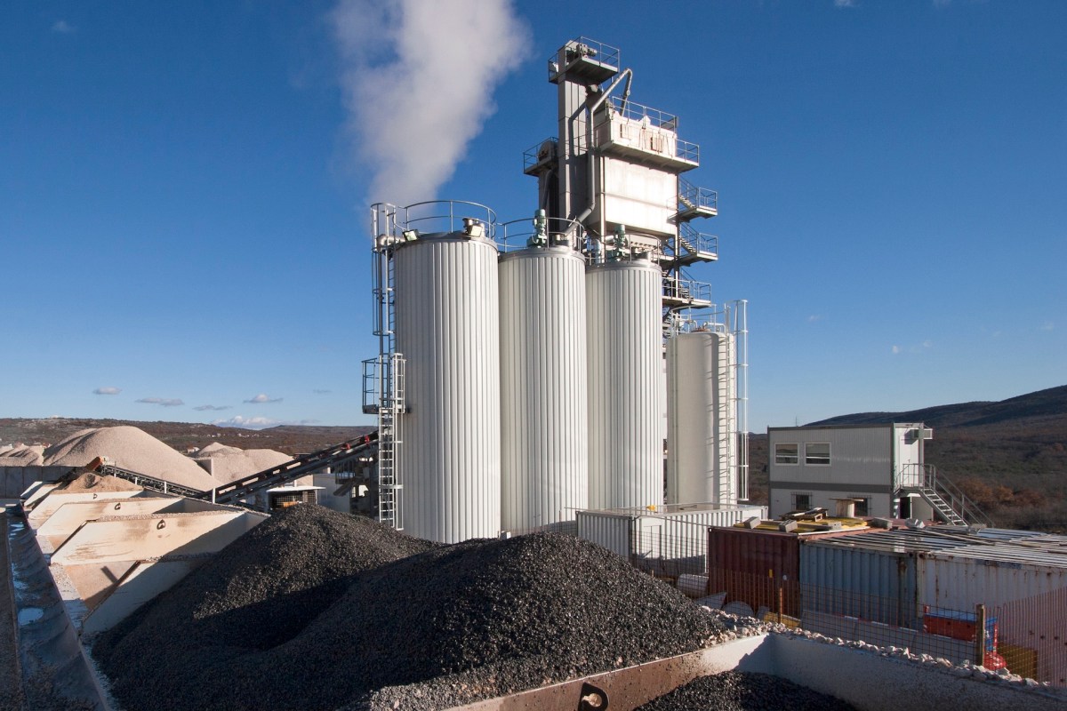 A storage facility with large silos and stockpiles of gravel and sand.
