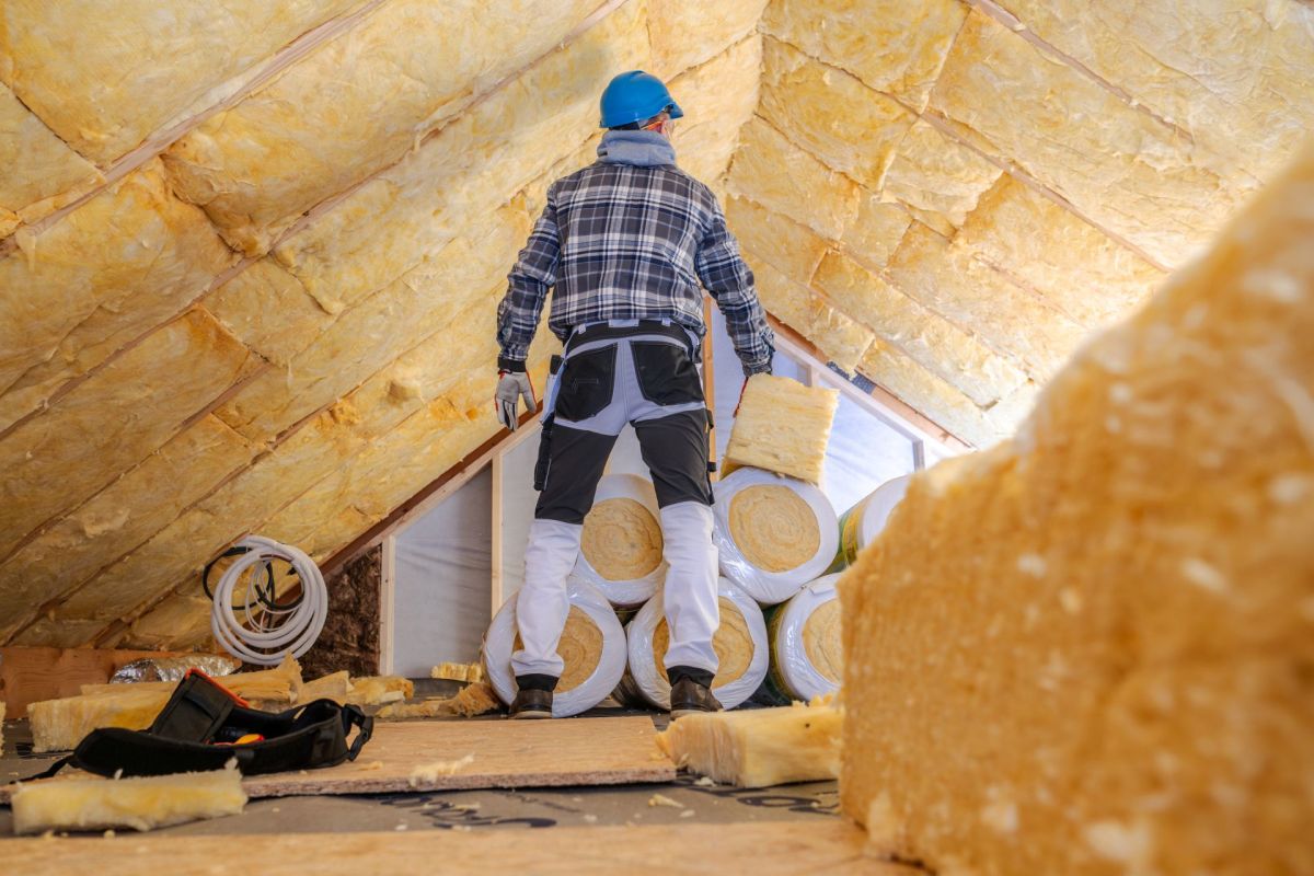 A worker insulating an attic.