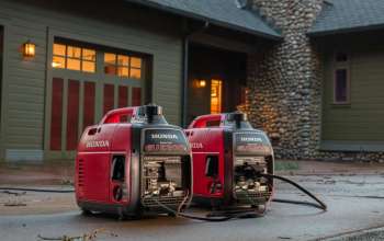 Two Honda EU2200i generators are positioned outside a house with stone and wooden features.