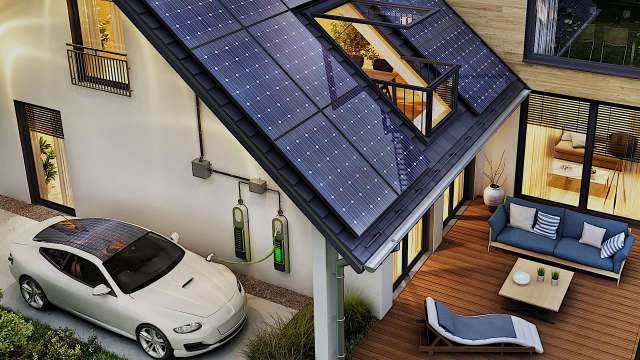 A modern house with solar panels on the roof and an electric vehicle charging station in the driveway.