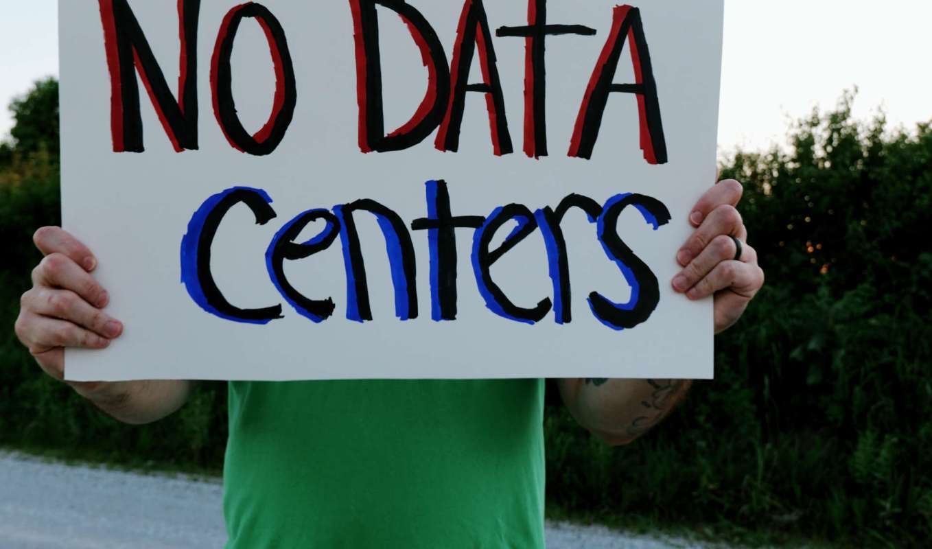 A person holds a sign that reads "NO DATA Centers" in colorful letters.