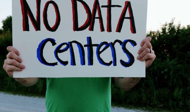 A person holds a sign that reads "NO DATA Centers" in colorful letters.