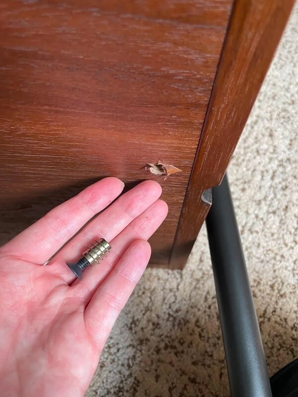 A black metal bracket attached to a wooden surface with a screw.
