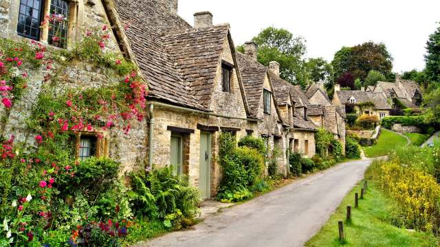 Stone cottages with flowers along a narrow road.