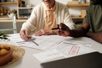 A woman and a man review financial documents on a table.