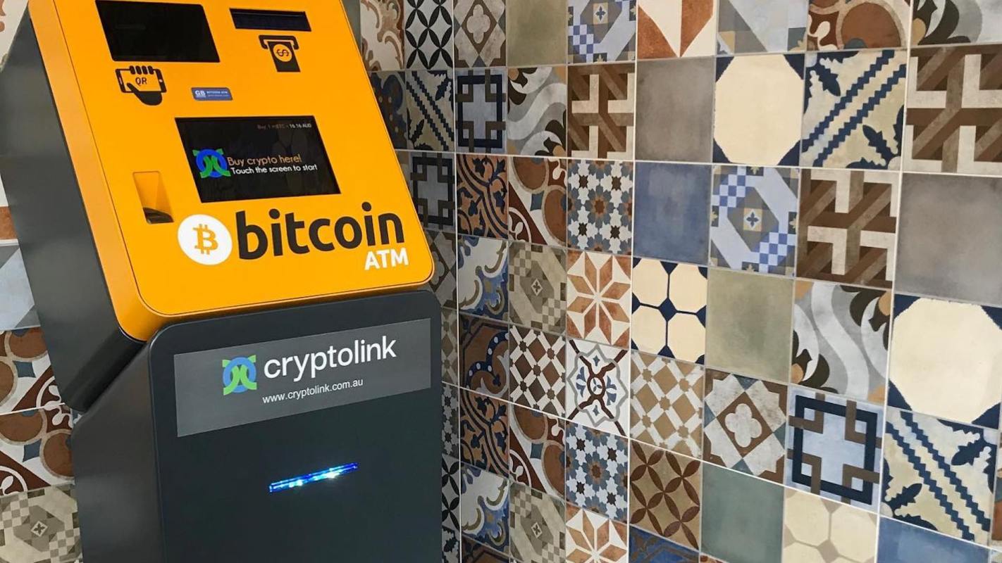 A Bitcoin ATM next to a colorful tiled wall.