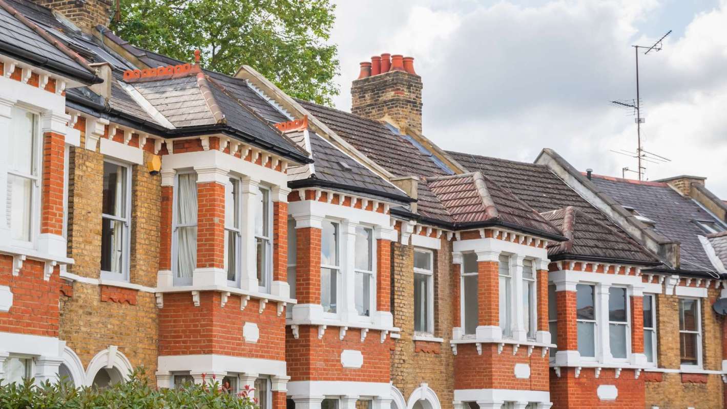 A row of traditional brick houses with distinct architectural features and sloped roofs.