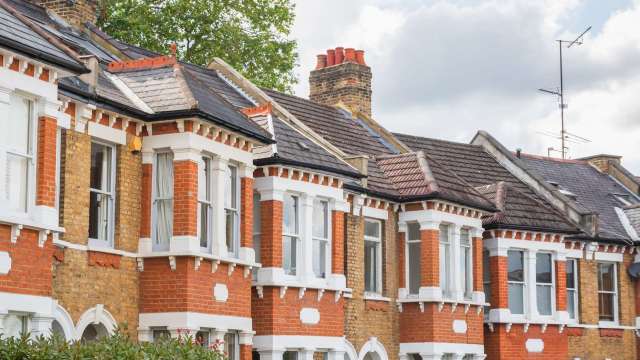 A row of traditional brick houses with distinct architectural features and sloped roofs.