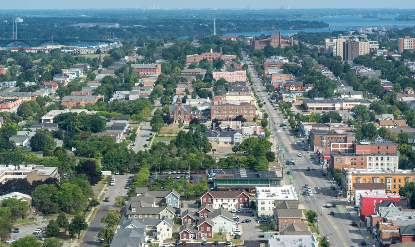 Aerial view of Buffalo, New York, with residential areas, streets, and a river in the background.