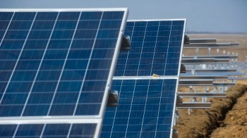 Solar panels arranged in a field with a clear sky in the background.