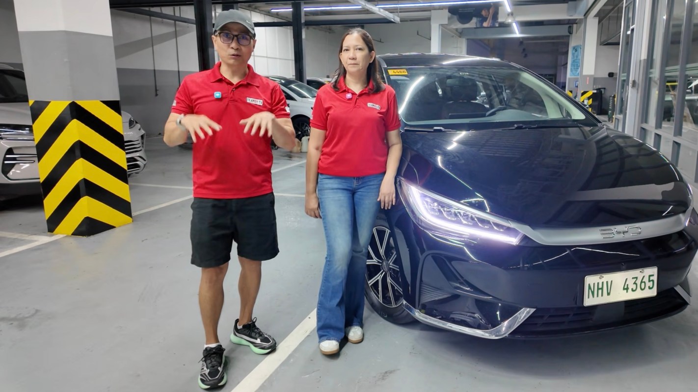 Two people standing beside a BYD eMax 7.