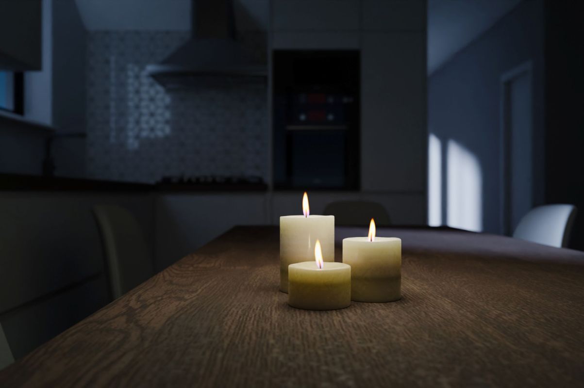 Three lit candles on a table in a darkened room.
