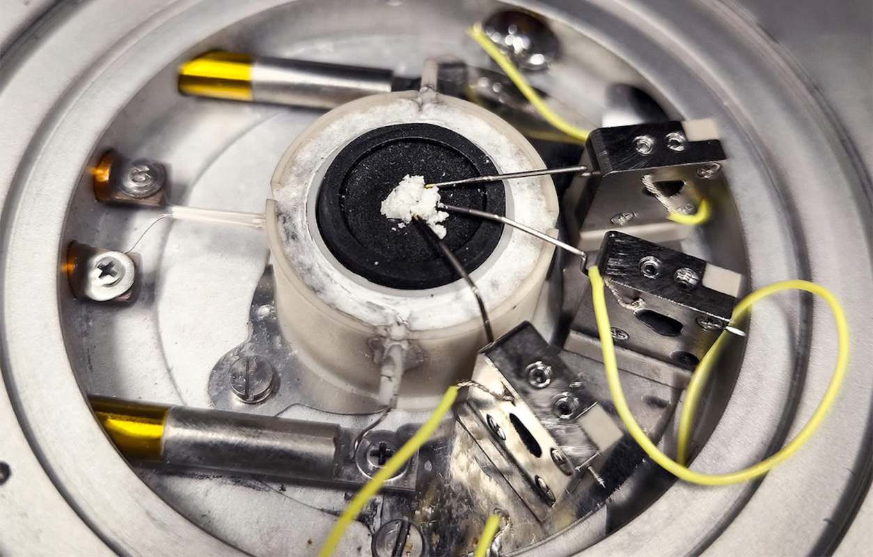 A close-up view of a scientific instrument with wires and a sample holder.