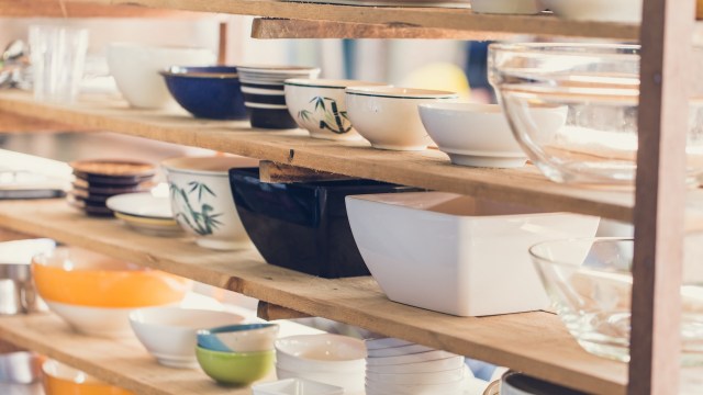 A wooden shelf displaying various bowls and glassware in different sizes and colors.
