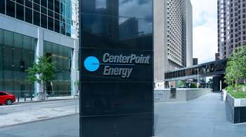 A sign for CenterPoint Energy outside a modern glass building in an urban setting.