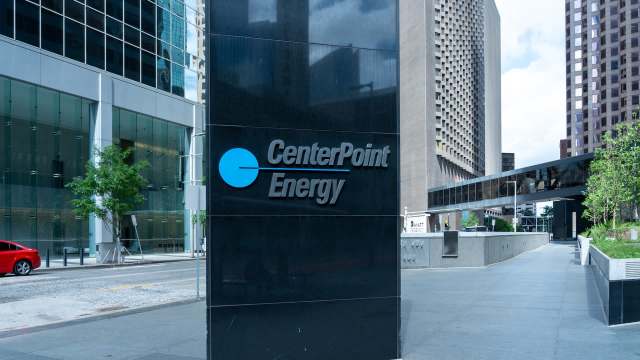 A sign for CenterPoint Energy outside a modern glass building in an urban setting.