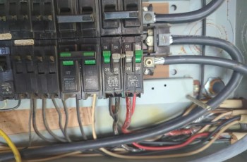 A circuit breaker panel with multiple switches and colorful electrical wires.