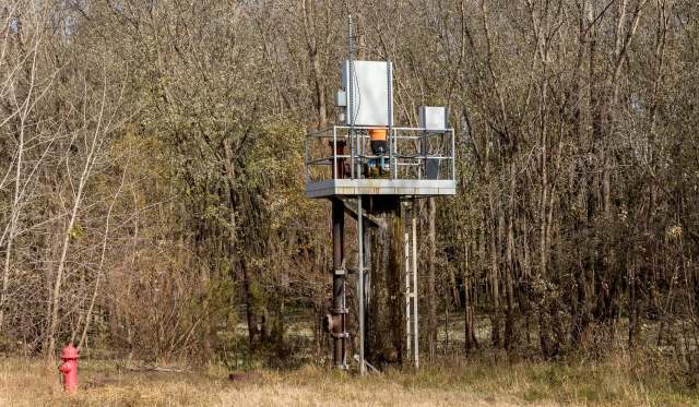 A metal platform with water pumping equipment surrounded by trees and a red fire hydrant nearby.