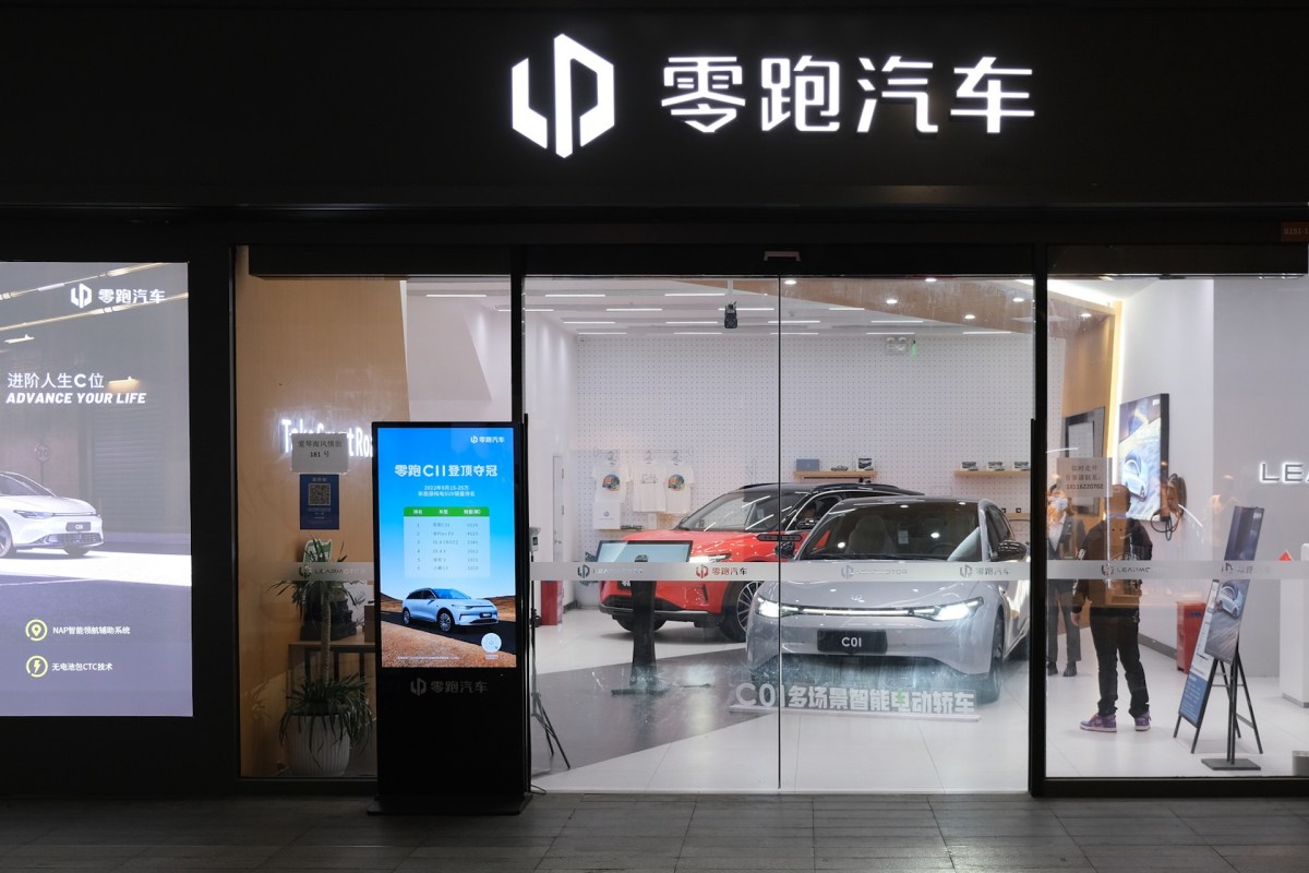 A storefront of a car dealership displaying several electric vehicles and promotional signage.