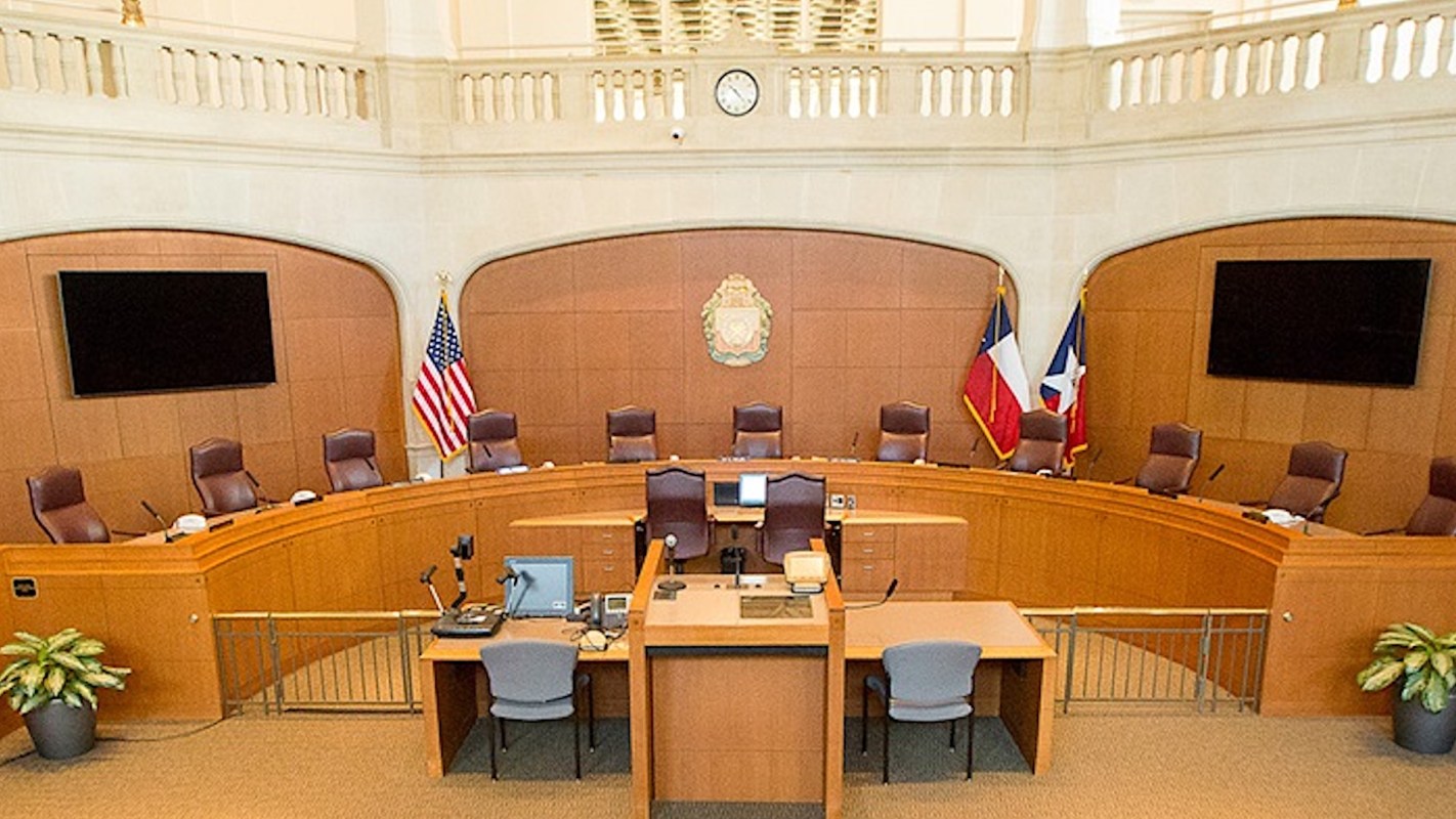 A courtroom setup featuring chairs, a podium, and flags displayed on the walls.