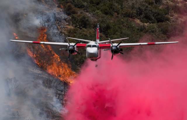 A firefighting plane drops red fire retardant.