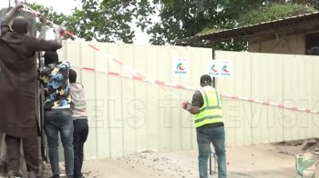 A group of people work together to secure a construction site with barriers and signage.