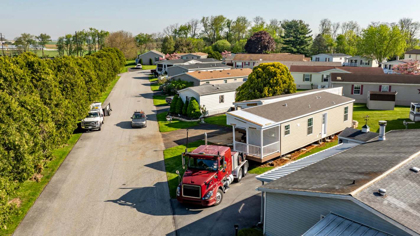 A residential mobile home community with parked vehicles and neatly trimmed lawns.