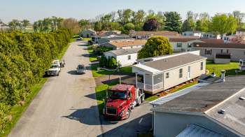 A residential mobile home community with parked vehicles and neatly trimmed lawns.