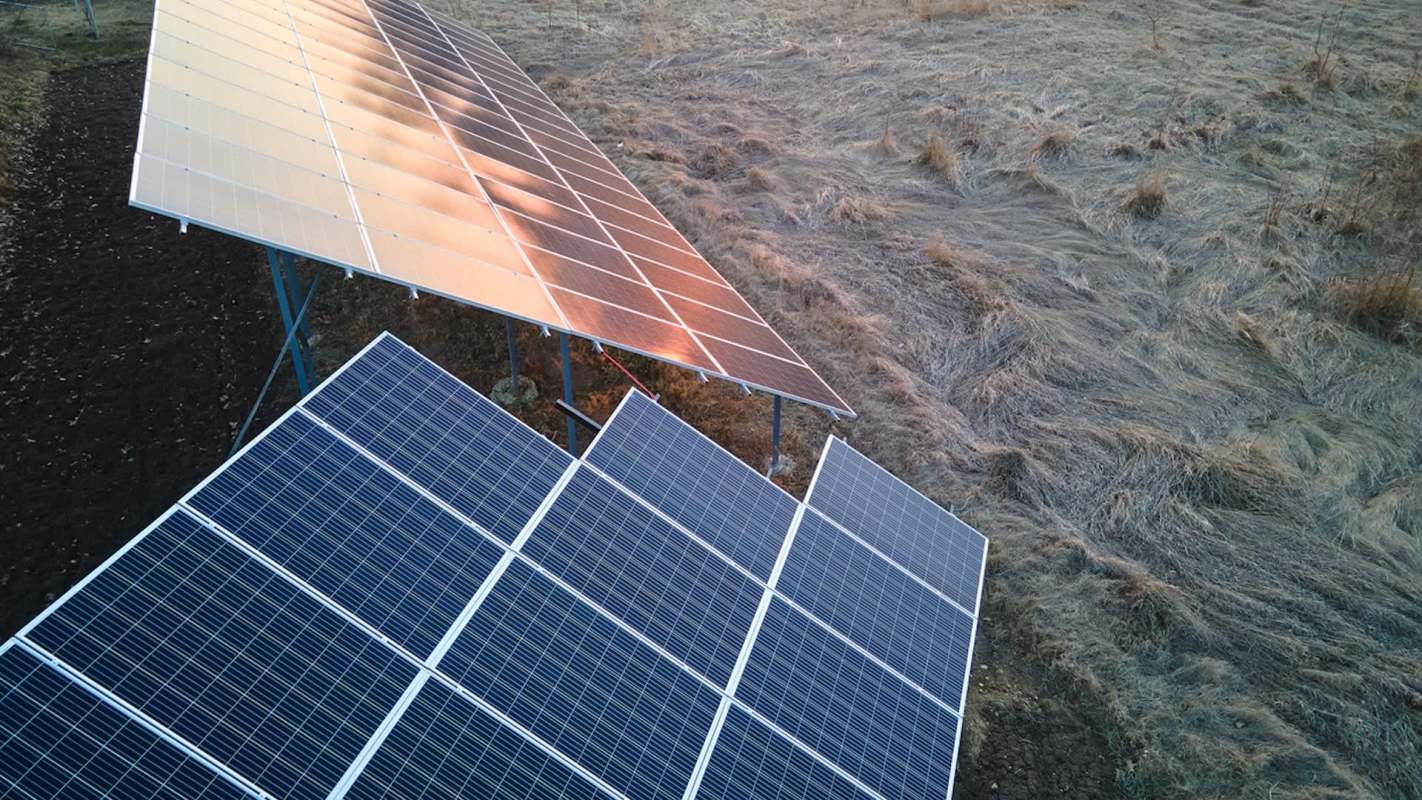A solar panel installation on a field with dry grass.