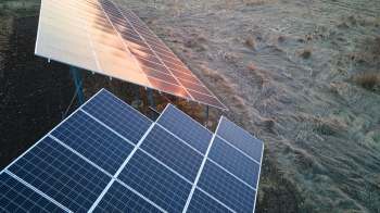 A solar panel installation on a field with dry grass.