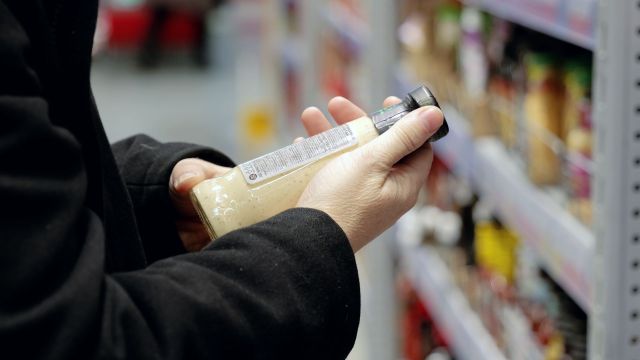 A shopper looking at a condiment's ingredient label.
