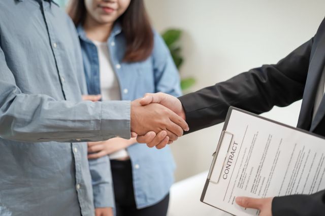 A couple shaking hands over a contract.