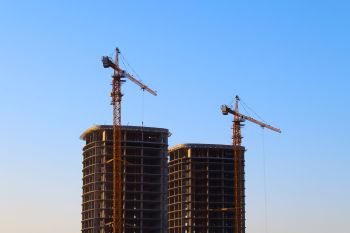 Cranes at a construction site with two towers.