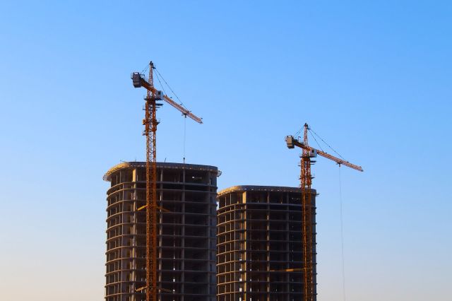 Cranes at a construction site with two towers.
