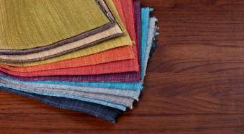 A stack of colorful fabric swatches arranged on a wooden surface.