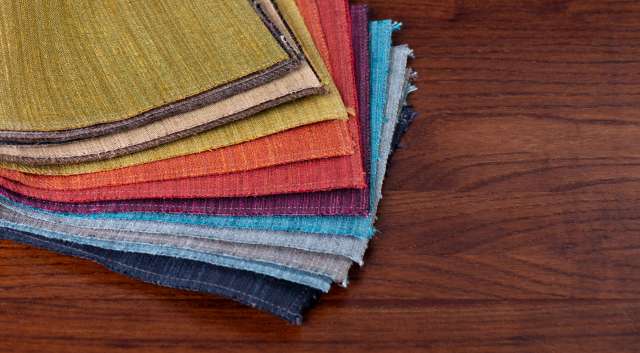 A stack of colorful fabric swatches arranged on a wooden surface.