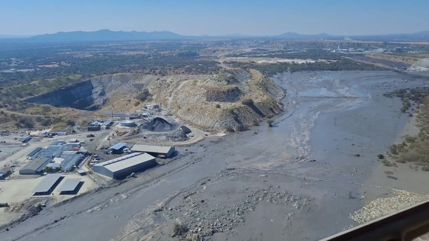 Aerial view of a mining site with hills, machinery, after a dam break