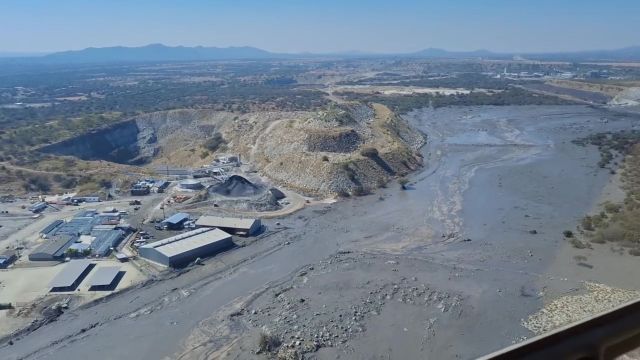 Aerial view of a mining site with hills, machinery, after a dam break