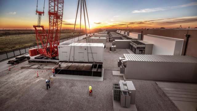 A construction site with large equipment and storage units at sunset.