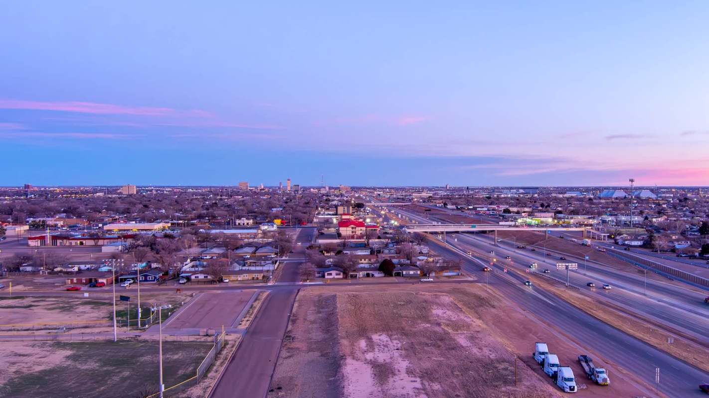 A view of Lubbock, Texas, with buildings, highways, and vehicles during twilight.