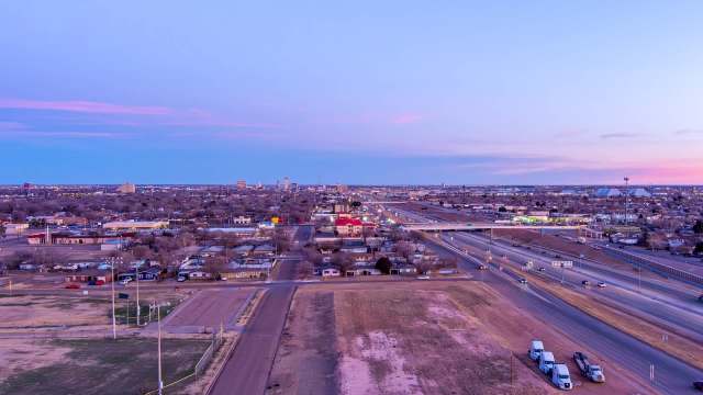 A view of Lubbock, Texas, with buildings, highways, and vehicles during twilight.