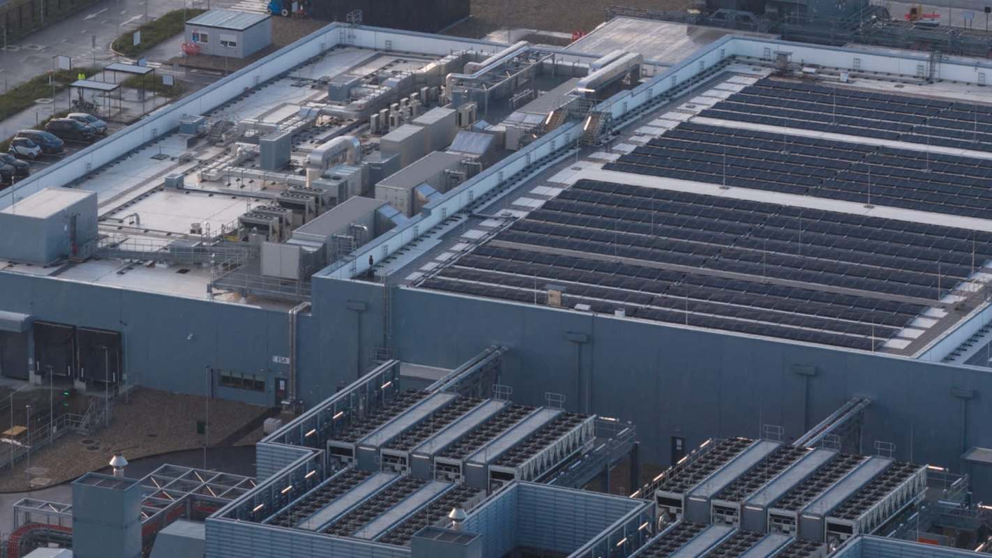 A large industrial building with solar panels and various mechanical equipment on the roof.