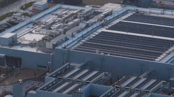 A large industrial building with solar panels and various mechanical equipment on the roof.