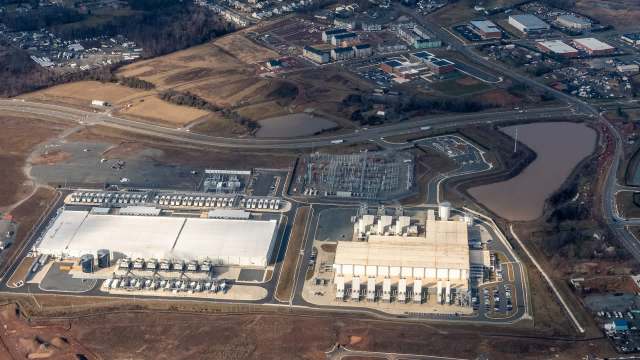 An industrial complex with data center buildings, parking lots, and surrounding roadways and fields.