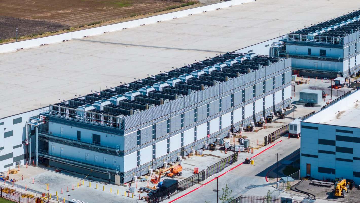 A data center complex with multiple exterior cooling units and construction equipment.