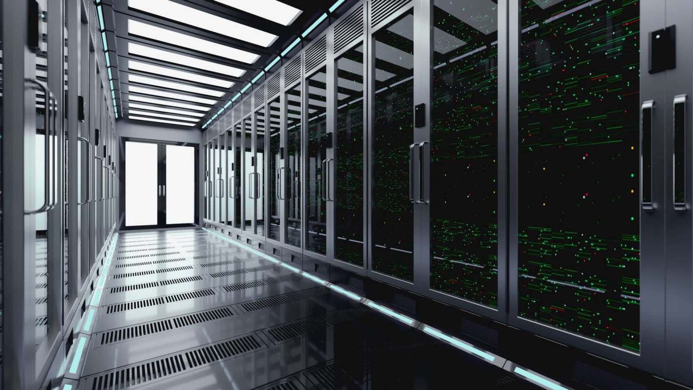 A data center corridor with server racks and digital displays along the walls.