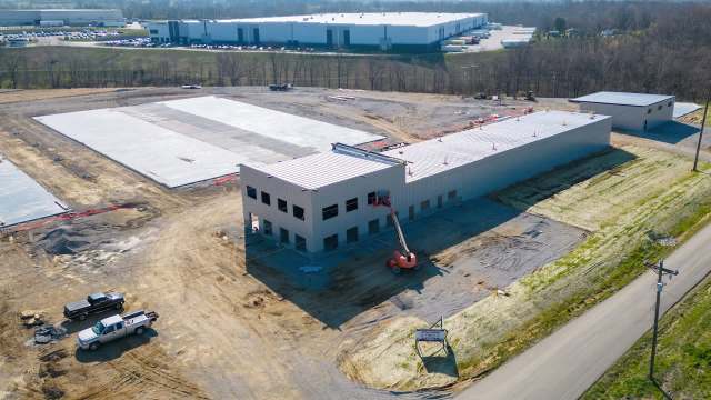 A construction site featuring a partially built warehouse and machinery on a gravel surface.